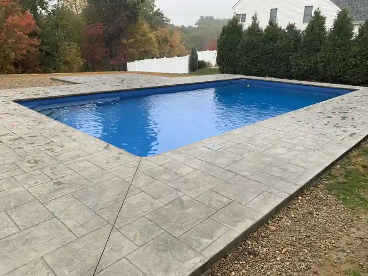 Liner pool on a stamped concrete deck with autumn foliage behind