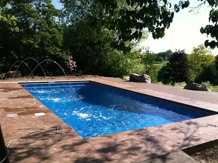 Copper-tone stamped deck with deck jets along the pool edge