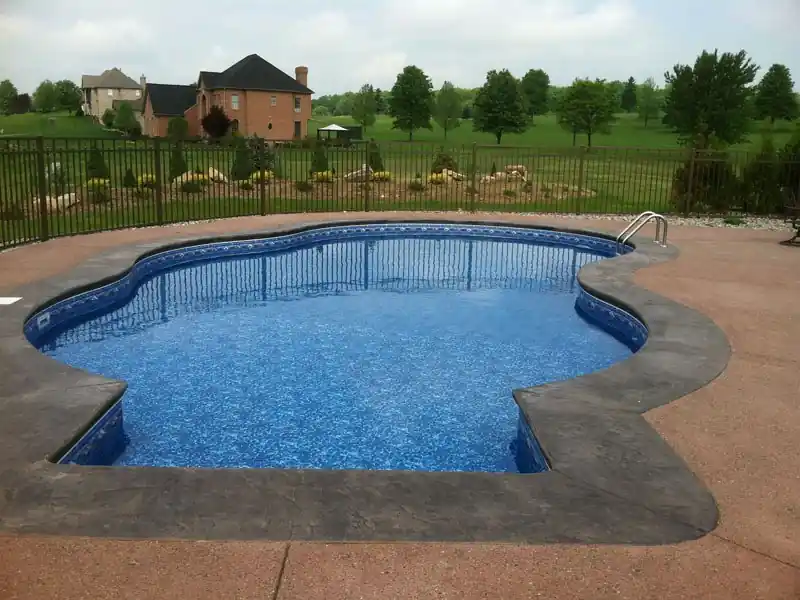 Freeform pool with a fence and golf course beyond