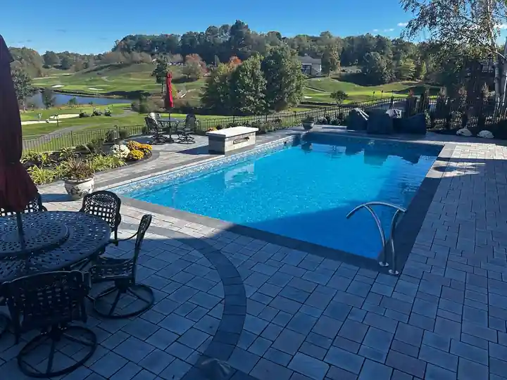 Open pool with a patio table set beside it and a golf course view beyond