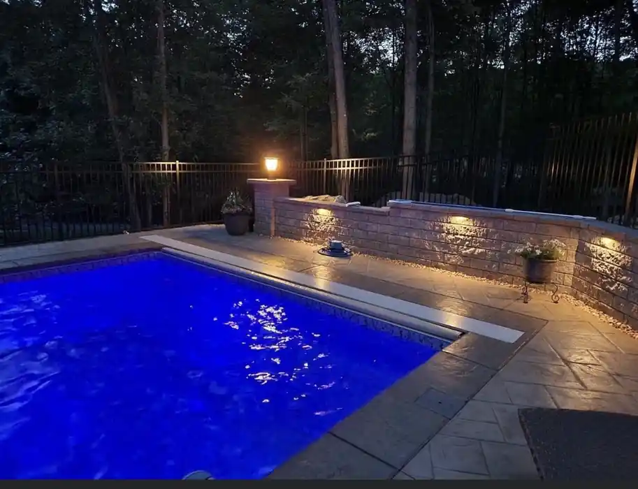 Pool lit blue at night against a stone wall