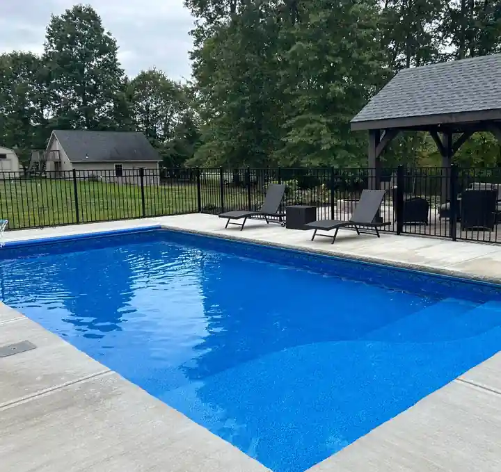 Finished pool beside a garden gazebo inside a black fence