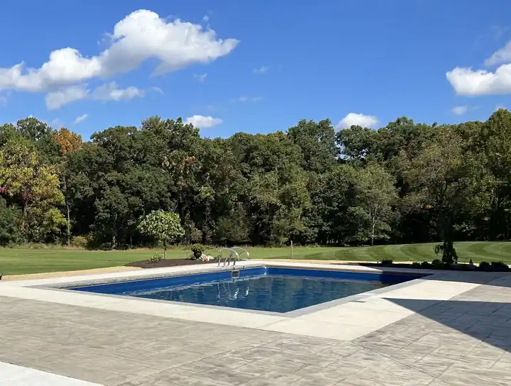 Pool set back under a big sky with a treeline beyond